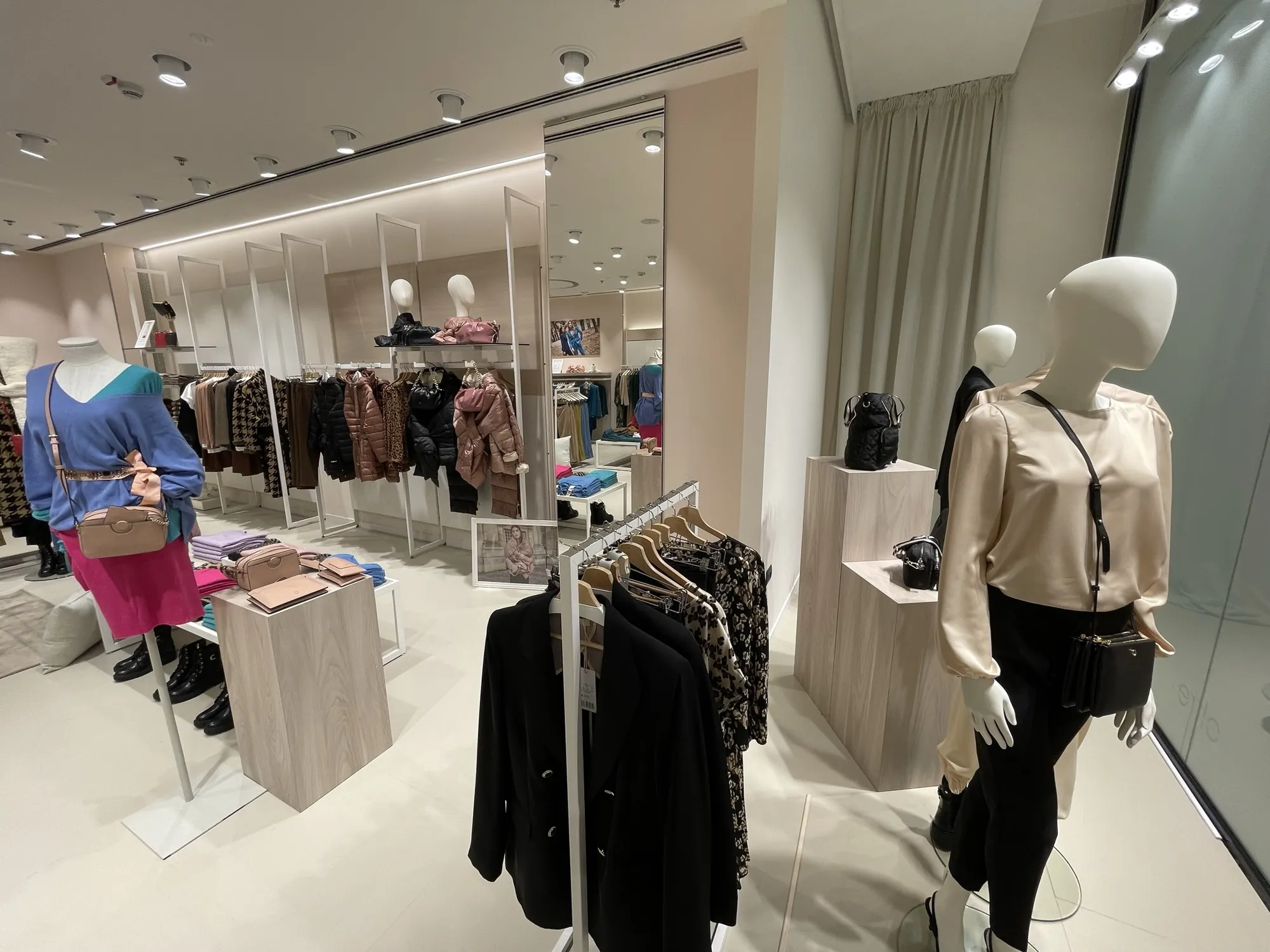 Negozio Oltre riqualificato: esposizione e pedane in legno chiaro