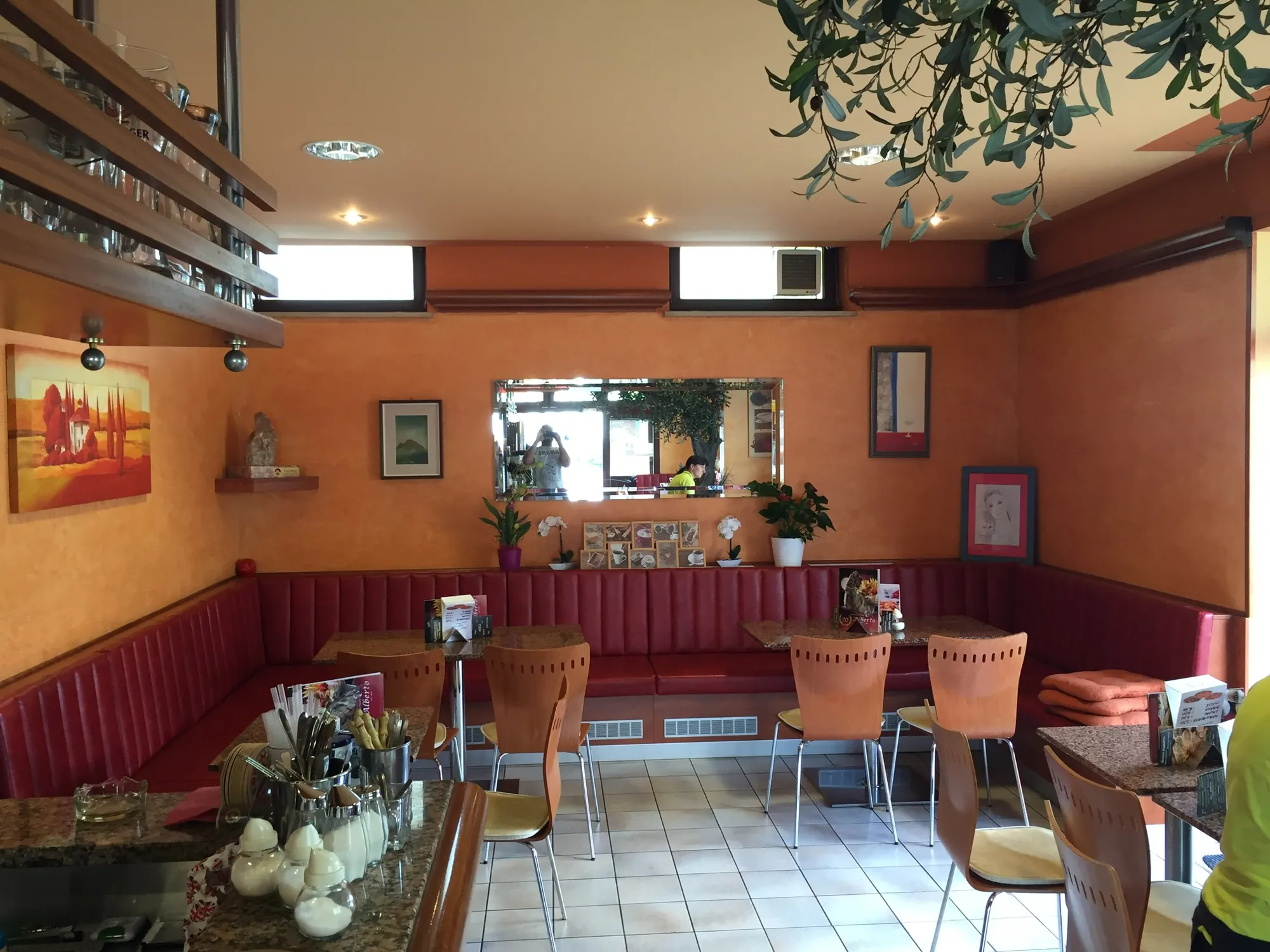 La parete di fondo con le pareti aranciate, lo specchio e le panche rosse, prima del restyling