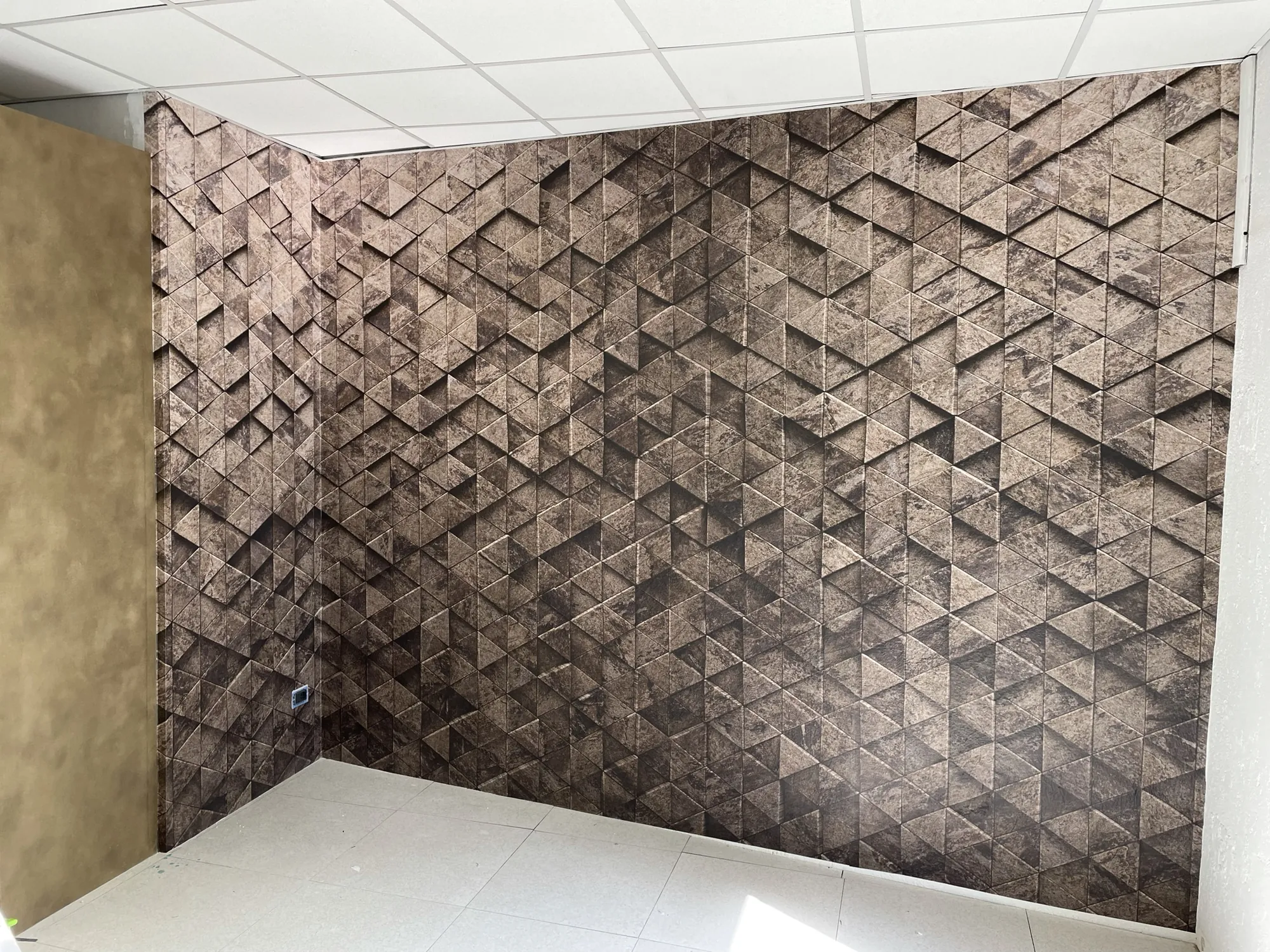 Parete con grafica geometrica effetto pietra scura stampata su vinile